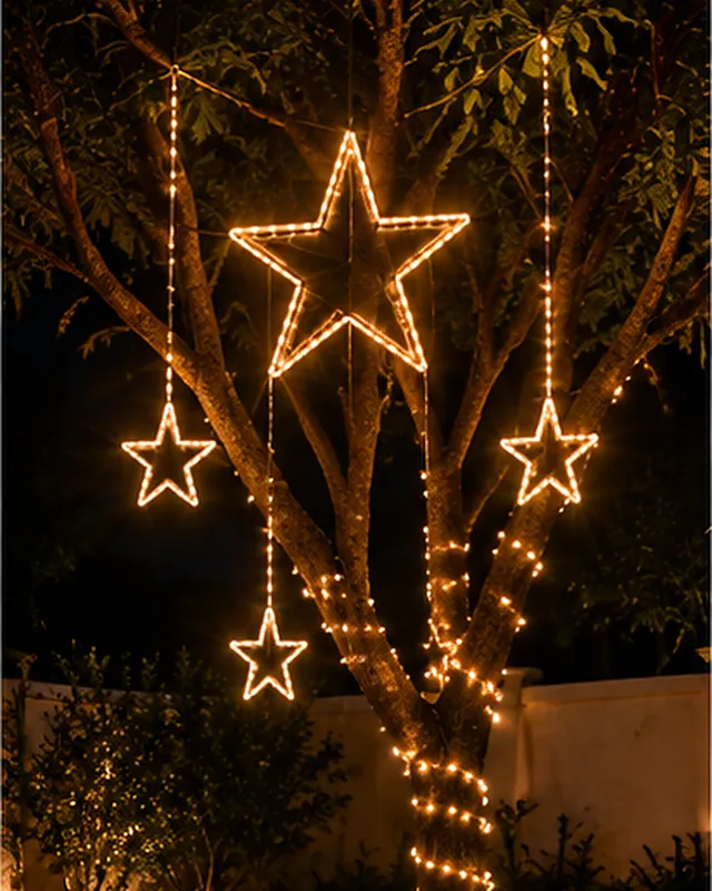 Estrelas planas iluminadas penduradas nos galhos de uma árvore no jardim à noite